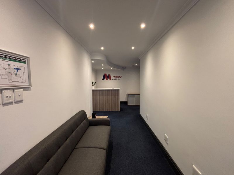 A professional office entrance area featuring a reception desk, recessed lighting, and clear emergency evacuation signage.