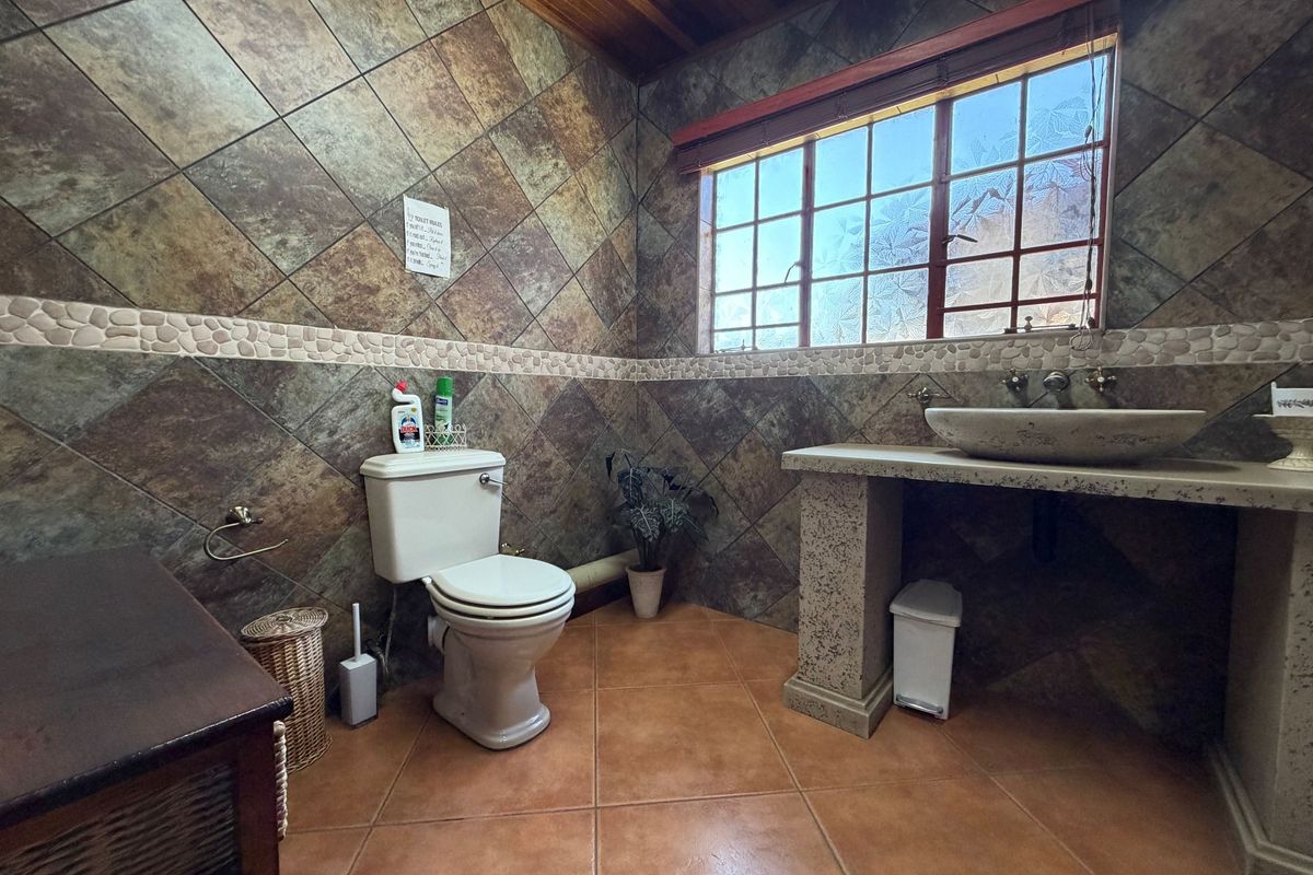 A rustic-style bathroom featuring stone wall tiles, a stone vessel sink on a concrete vanity, and a timber ceiling.