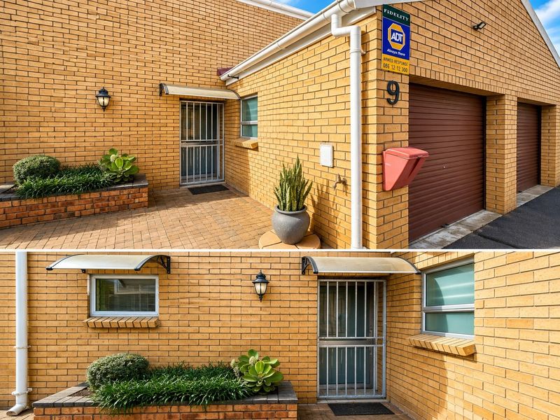 Front entrance area featuring a brick facade, security gate, garage access, and a built-in brick planter box.