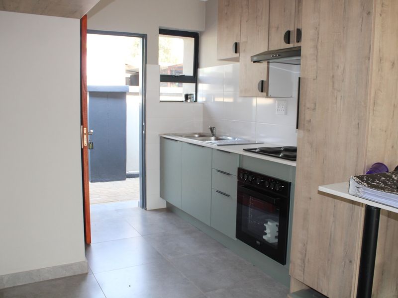 A functional kitchen featuring modern cabinetry, built-in oven and hob, tiled backsplash, and direct access to an outdoor area.