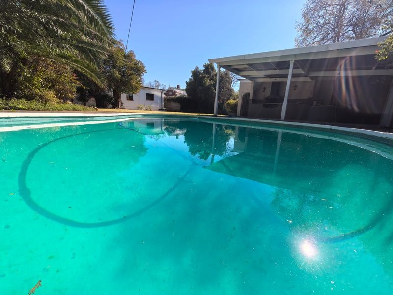 Outdoor pool area featuring a swimming pool and a covered patio with a built-in braai, ideal for outdoor entertaining.