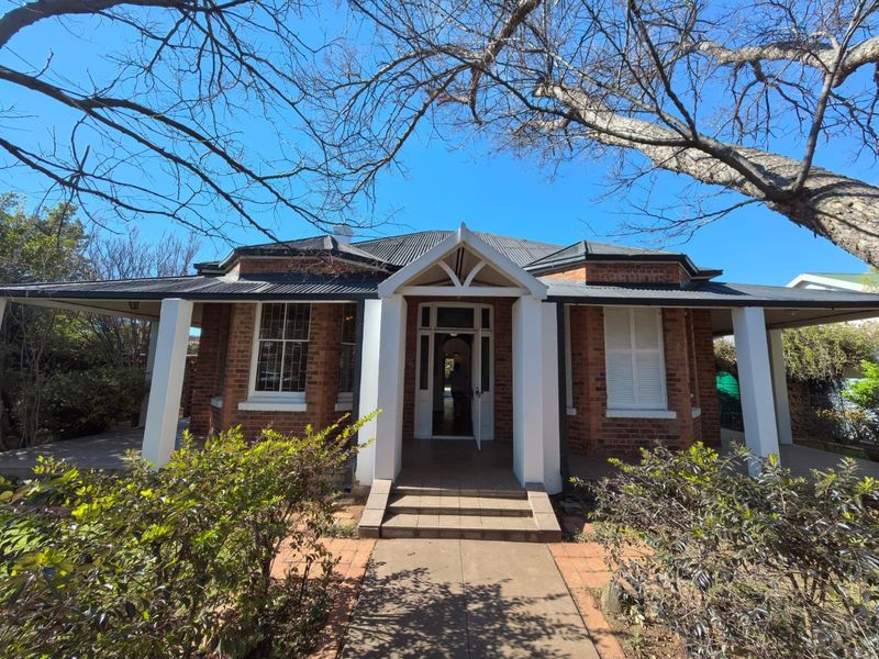 A charming brick-faced house featuring a covered veranda, classic timber sash windows with shutters, and a welcoming central entrance.