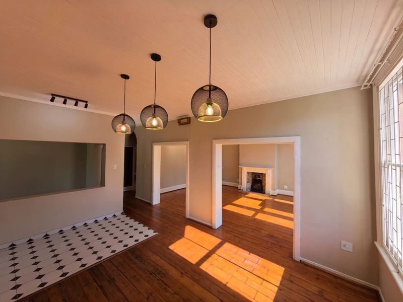 Spacious living area featuring original timber flooring, a decorative fireplace, and a unique pass-through window connecting to the adjacent space.