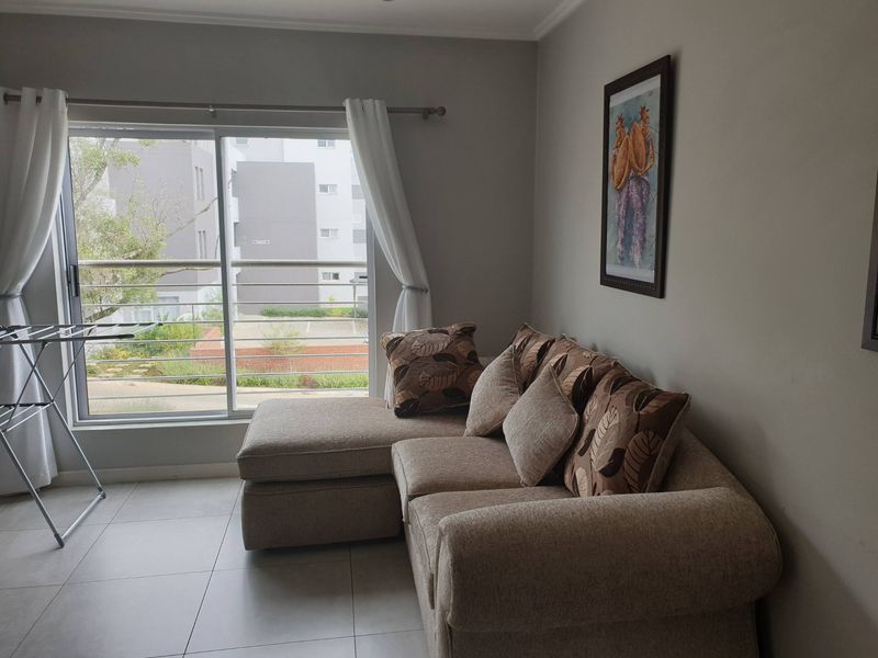 A living room featuring tiled flooring and a large sliding glass door that opens onto a balcony with metal railings.