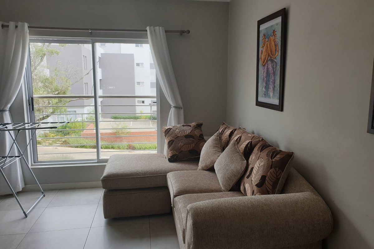 A living room featuring tiled flooring and a large sliding glass door that opens onto a balcony with metal railings.