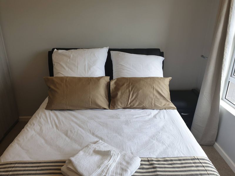 A cozy bedroom featuring neutral wall tones, a built-in wardrobe, and natural light from the adjacent window.