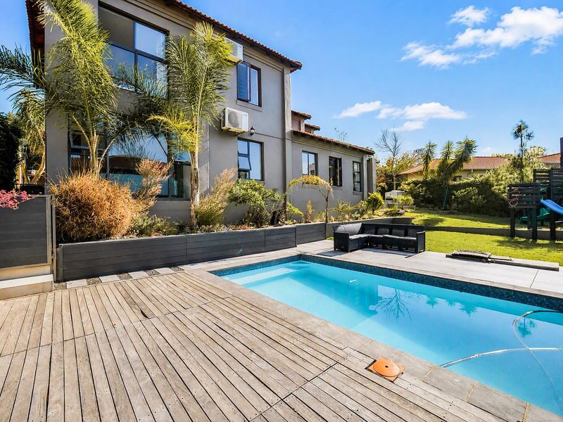 Rear garden area featuring a swimming pool, timber decking, and a paved patio area adjacent to the main house structure.