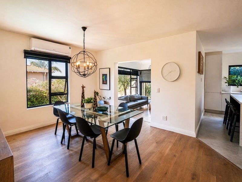 Open-plan dining and kitchen area featuring modern laminate flooring, stone island bench, and split-system air conditioning with seamless flow to the adjacent living space.