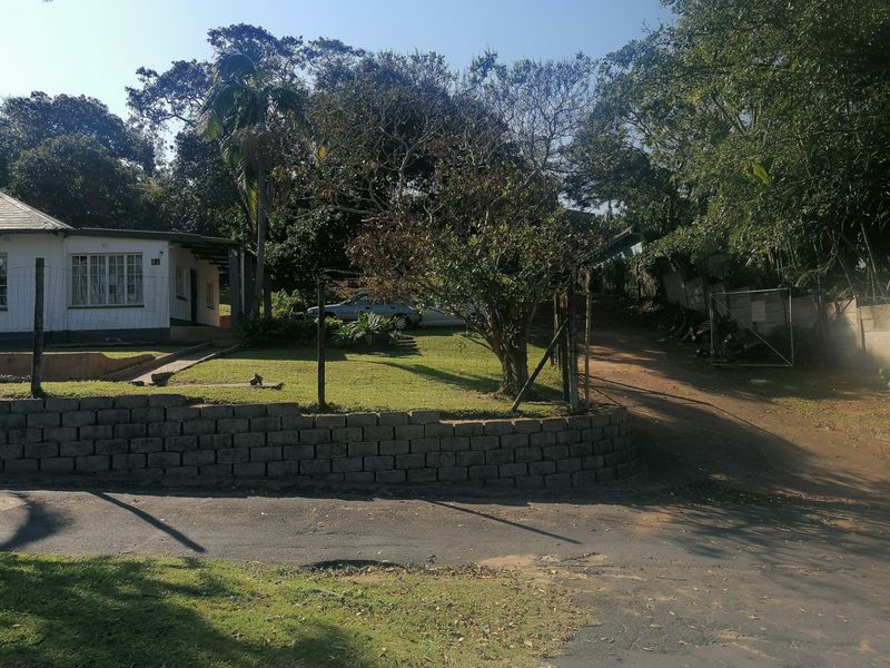 Front view of the property featuring a landscaped garden, a retaining wall, and a driveway entrance.