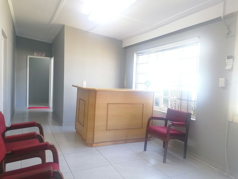 Entrance area featuring a built-in reception desk, tiled flooring, and natural light from a large window with security bars.