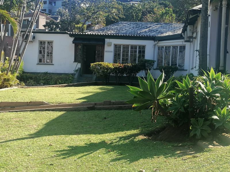Front view of a single-story residence featuring a tiled roof, timber-framed windows, and a well-maintained garden area.