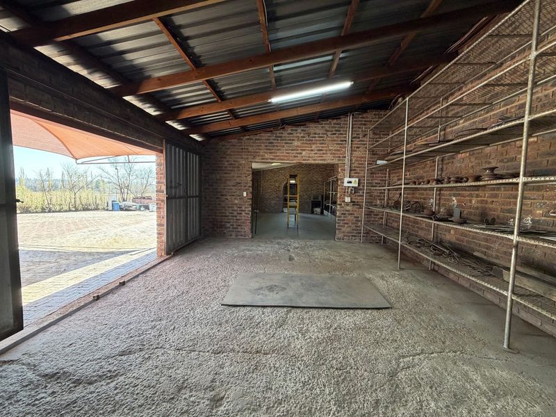 Spacious industrial utility area featuring exposed brick walls, concrete flooring, and extensive built-in metal shelving, suitable for storage or workshop use.