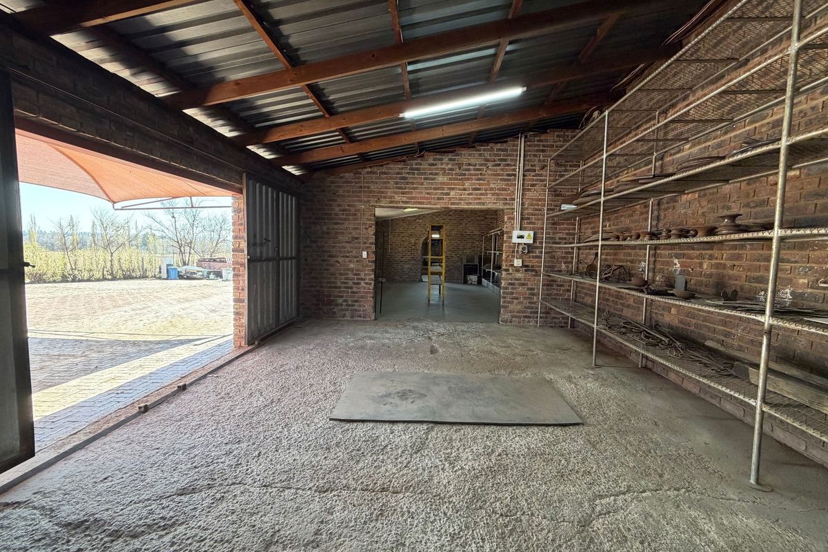 Spacious industrial utility area featuring exposed brick walls, concrete flooring, and extensive built-in metal shelving, suitable for storage or workshop use.