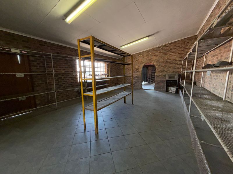 A spacious utility or storage room featuring exposed brick walls, tiled flooring, and an arched entryway, suitable for various industrial or commercial storage purposes.