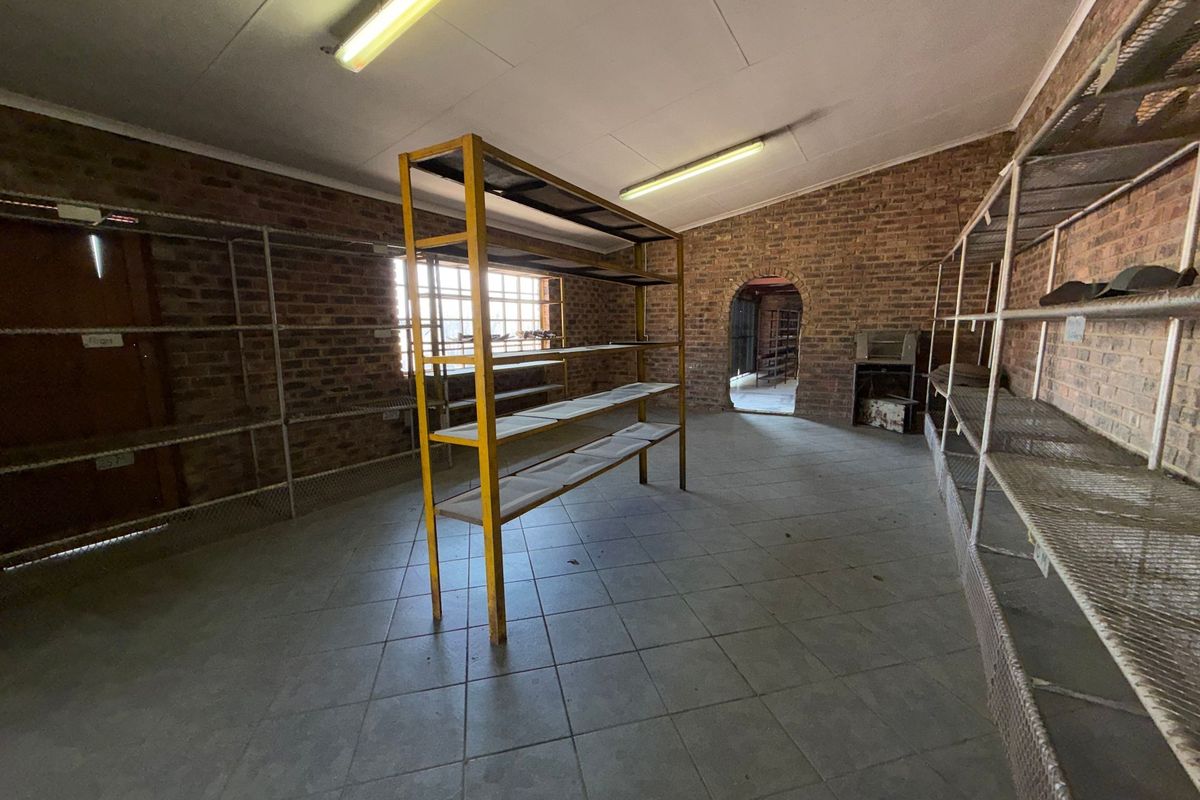A spacious utility or storage room featuring exposed brick walls, tiled flooring, and an arched entryway, suitable for various industrial or commercial storage purposes.