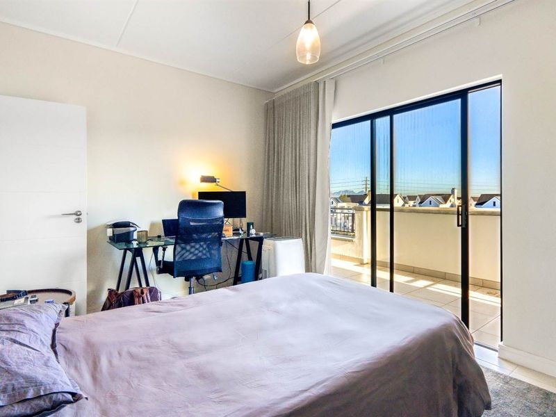 A bright bedroom featuring tiled flooring and a large sliding glass door that provides direct access to a private balcony.