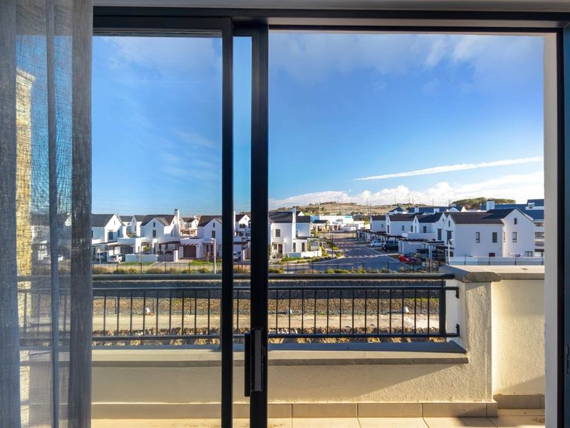 A clear view of the surrounding residential estate from a private balcony with modern sliding glass doors and a secure metal railing.