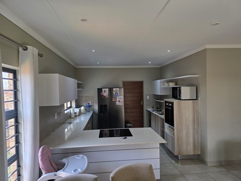 Modern kitchen featuring white cabinetry, stone countertops, integrated hob and oven, and recessed lighting, offering a clean and functional workspace.