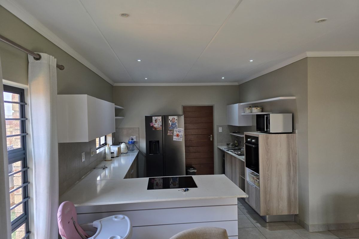 Modern kitchen featuring white cabinetry, stone countertops, integrated hob and oven, and recessed lighting, offering a clean and functional workspace.