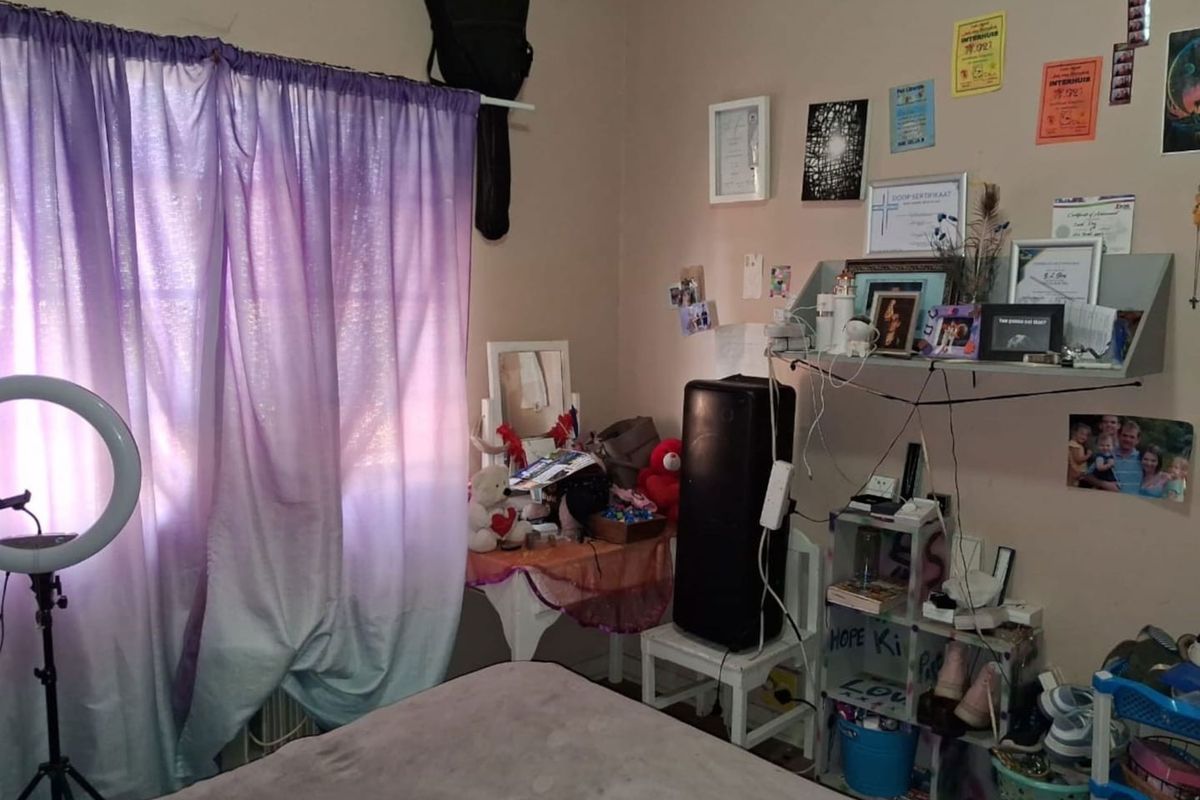 A bedroom featuring a window with curtain rod and standard electrical fixtures, providing a functional space for rest.