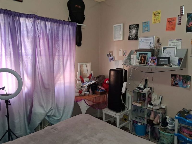 A bedroom featuring a window with curtain rod and standard electrical fixtures, providing a functional space for rest.