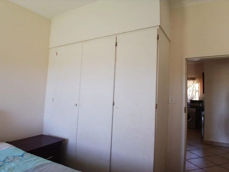 A bedroom featuring built-in cupboards with overhead storage, providing functional storage space within the room.