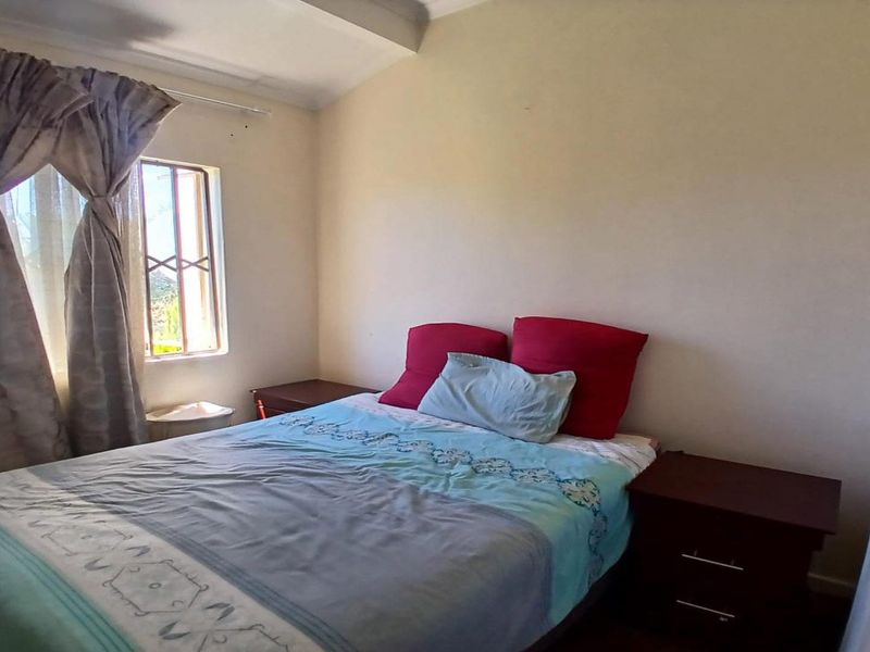 A standard bedroom featuring a window with an integrated security gate, providing natural light and basic ventilation.