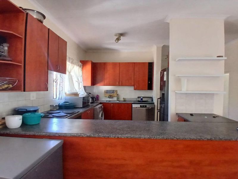 Functional kitchen featuring laminate cabinetry, granite countertops, built-in stove, and integrated dishwasher with a breakfast bar counter.