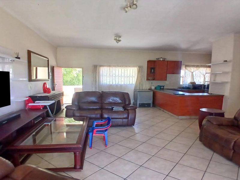 Open plan living and kitchen area featuring tiled flooring, a breakfast bar, and direct access to the exterior.