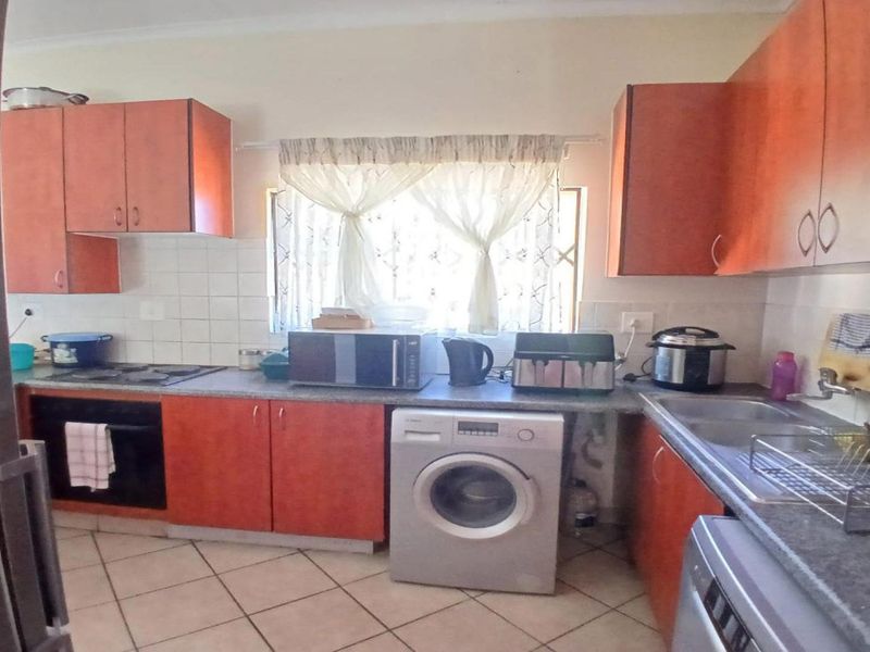 A functional kitchen featuring wood-finish cabinetry, laminate countertops, a built-in oven, hob, and tiled flooring with a practical layout.