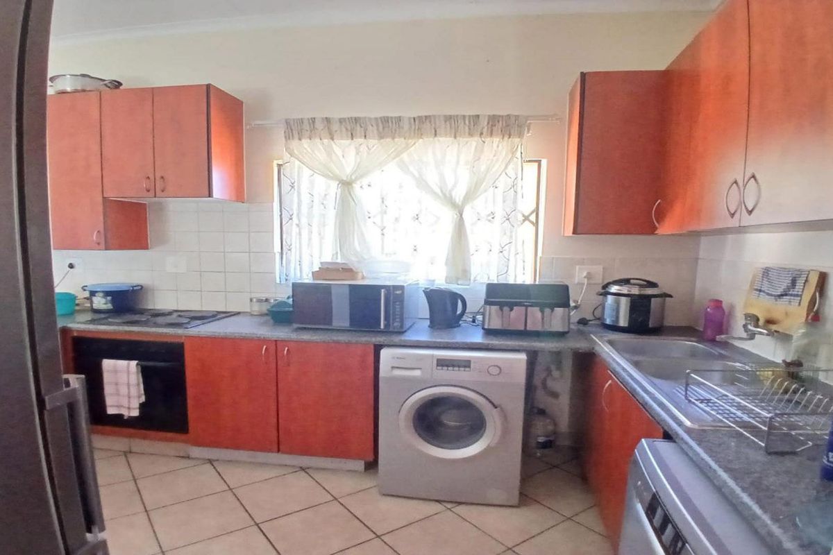 A functional kitchen featuring wood-finish cabinetry, laminate countertops, a built-in oven, hob, and tiled flooring with a practical layout.
