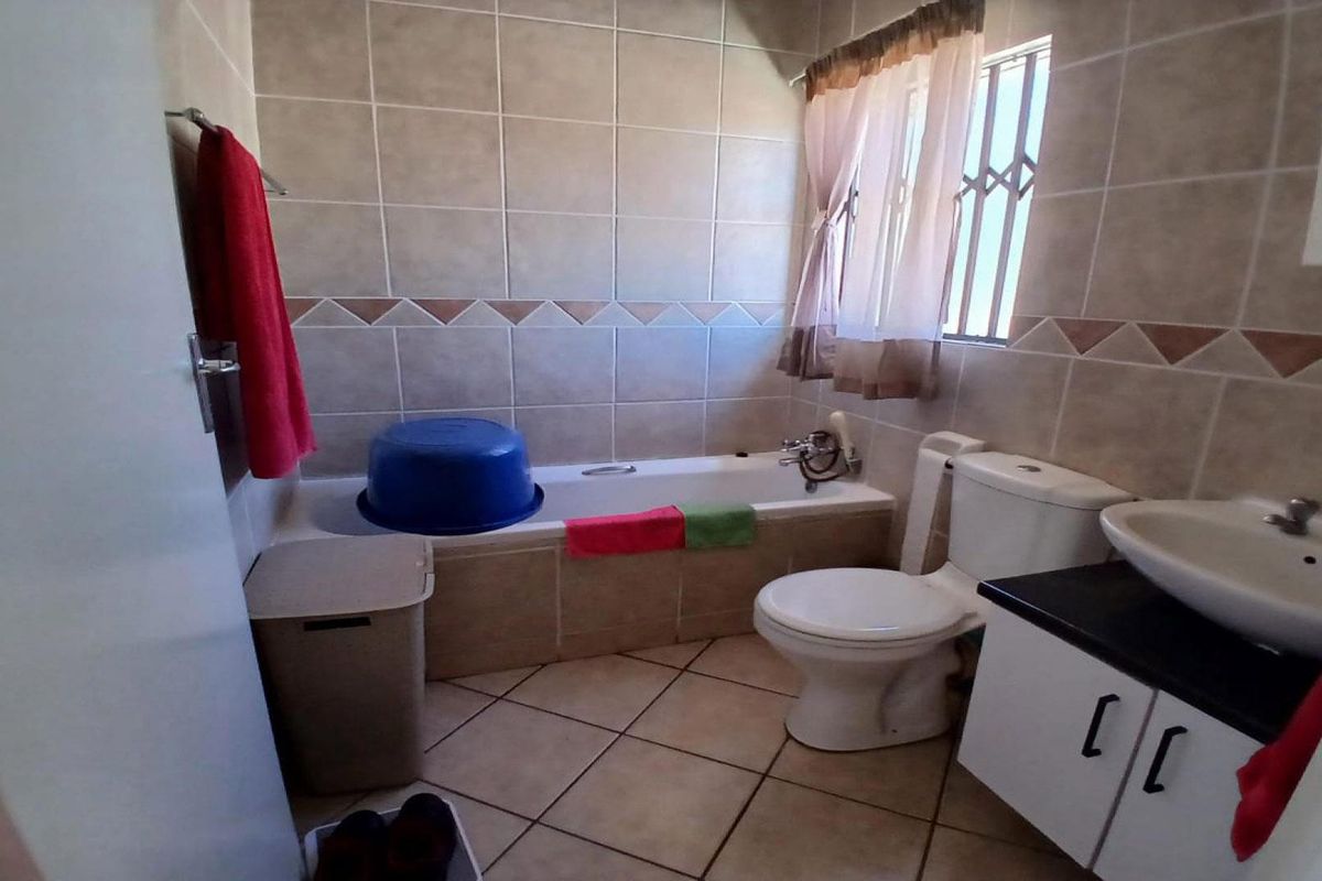 A functional bathroom featuring a bathtub, toilet, and vanity basin with tiled finishes throughout.