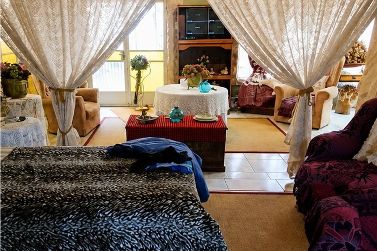 A living area featuring tiled flooring and a built-in media cabinet, with access to an exterior door.