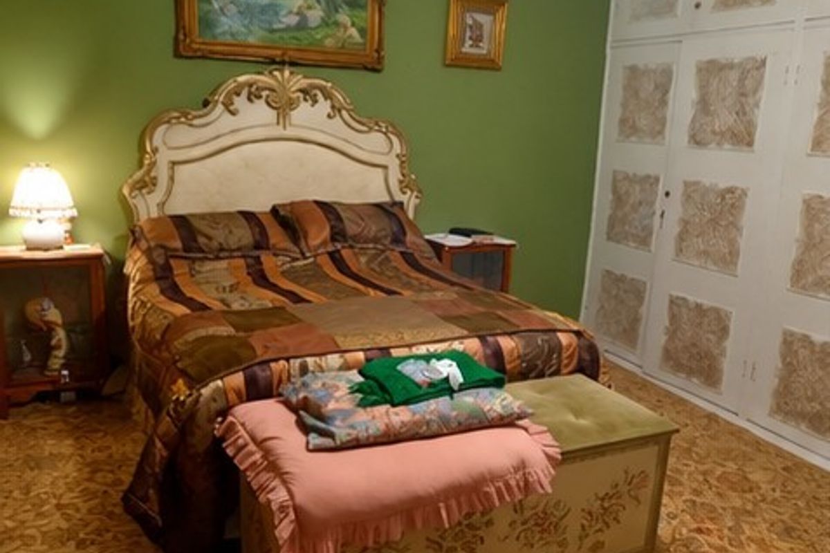A bedroom featuring built-in cupboards and patterned carpet flooring, requiring cosmetic updates to modernize the space.