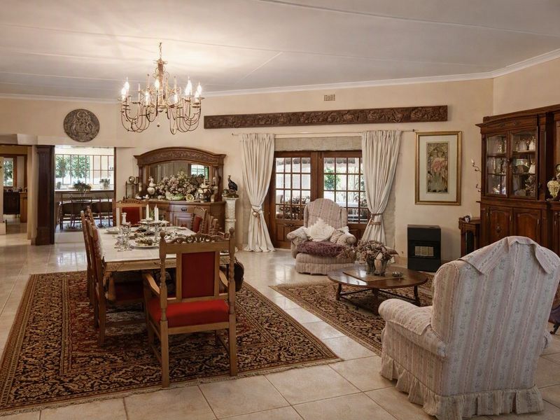 Spacious open-plan living and dining area featuring tiled floors, decorative wooden accents, and direct access to the outdoor patio through wooden framed glass doors.