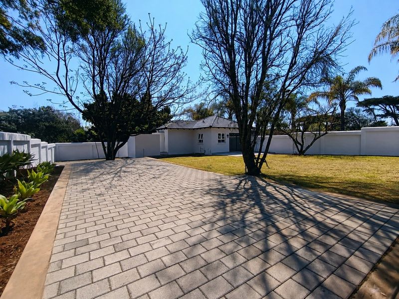 Spacious rear garden featuring a paved driveway, well-maintained lawn, and secure perimeter walling surrounding the cottage property.