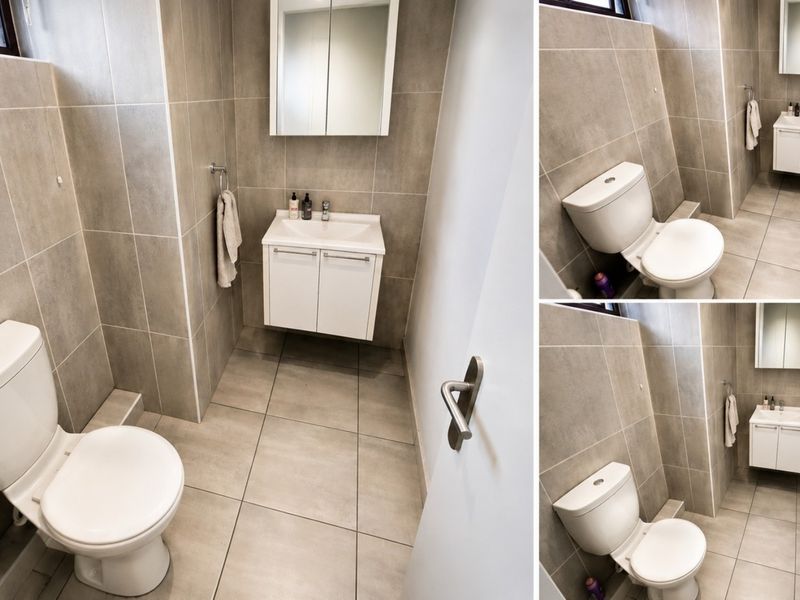 A modern, compact bathroom featuring neutral floor-to-ceiling tiling, a wall-mounted vanity with a basin, and a dual-flush toilet.