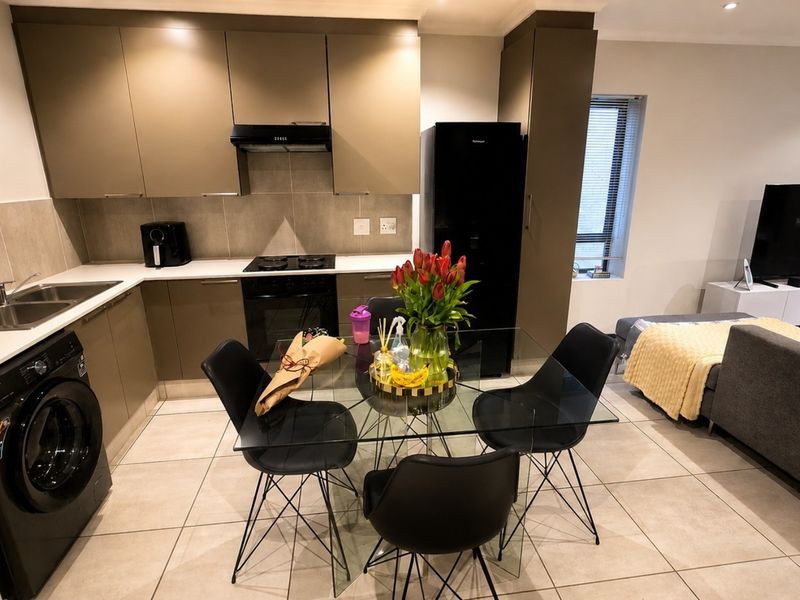 Modern open-plan kitchen featuring sleek cabinetry, integrated appliances, and tiled flooring, seamlessly flowing into the adjacent living area.