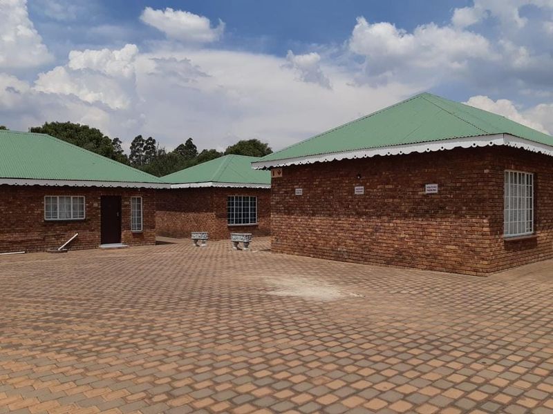 Exterior view of face brick residential buildings featuring green metal roofing and a large paved courtyard area.