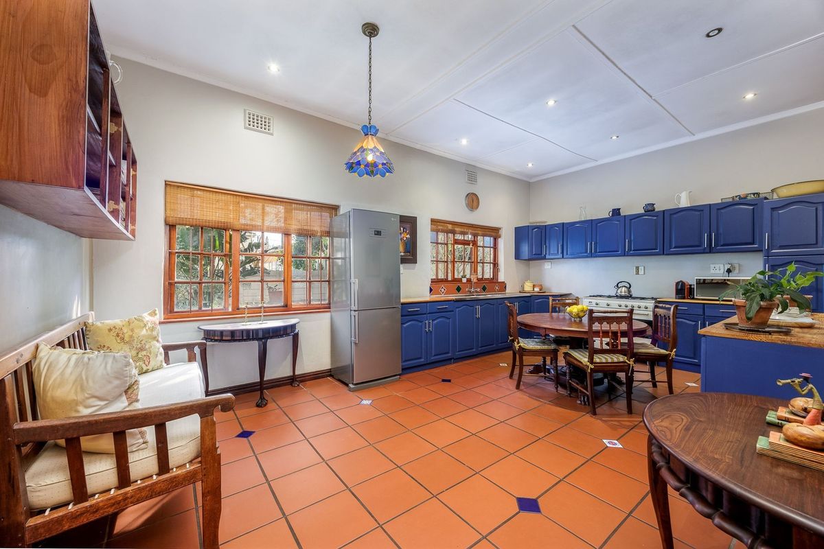 Spacious kitchen featuring blue cabinetry, terracotta tiled flooring, and a gas stove, offering a functional layout with ample space for a dining area.