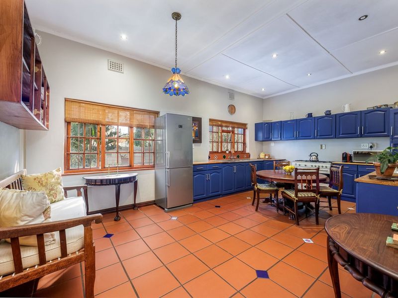 Spacious kitchen featuring blue cabinetry, terracotta tiled flooring, and a gas stove, offering a functional layout with ample space for a dining area.