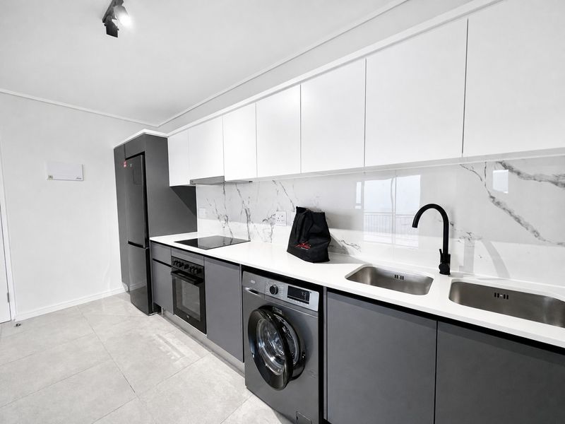 Modern kitchen featuring sleek grey and white cabinetry, marble-look splashback, integrated appliances, and high-quality finishes throughout.