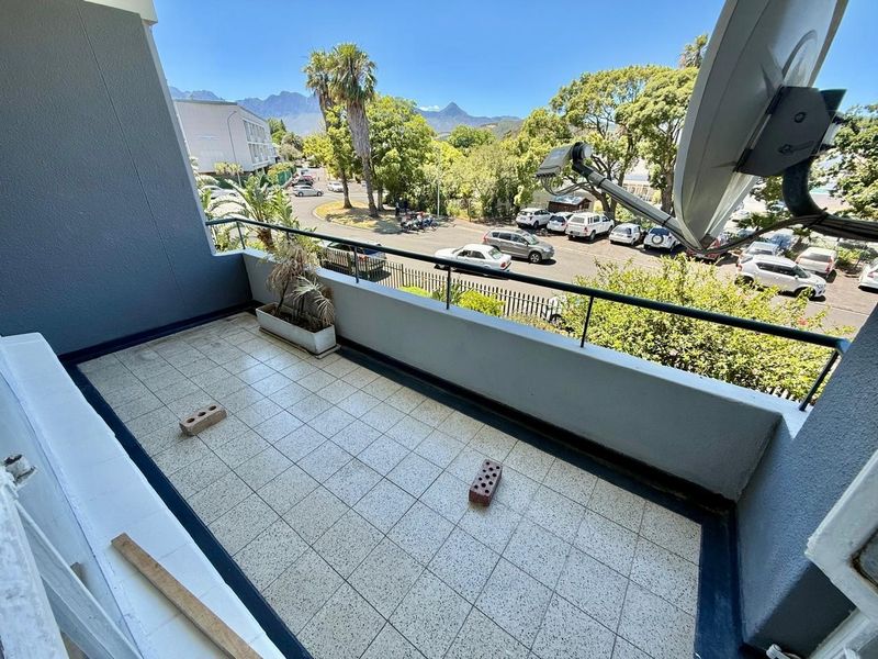 A spacious balcony featuring tiled flooring and metal railings, offering an elevated view of the surrounding street and neighborhood.