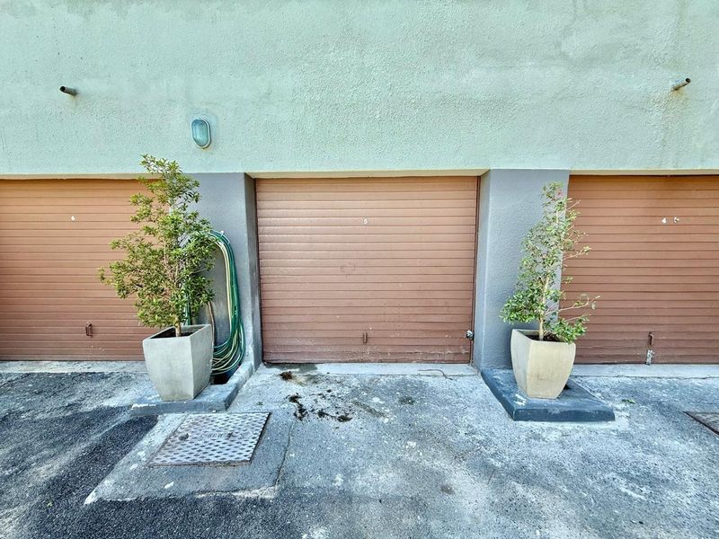 A view of multiple garage units featuring roller shutter doors and a concrete driveway area.