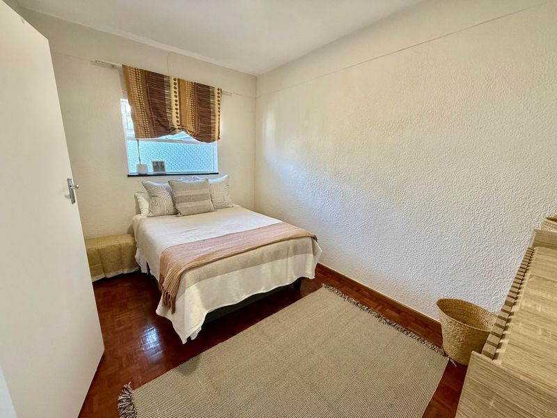 A cozy bedroom featuring warm parquet flooring and textured walls, providing a comfortable and functional living space.