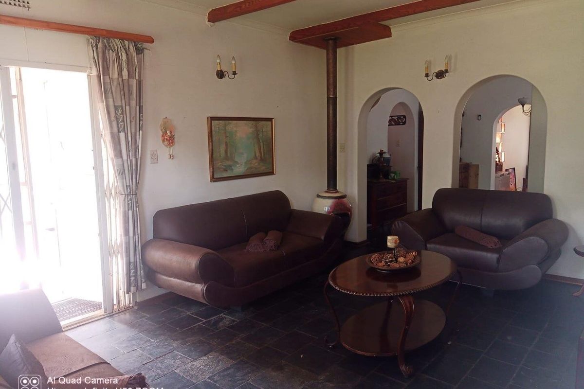 Living room featuring slate tile flooring, exposed timber ceiling beams, a freestanding fireplace, and arched doorways leading to adjacent spaces.