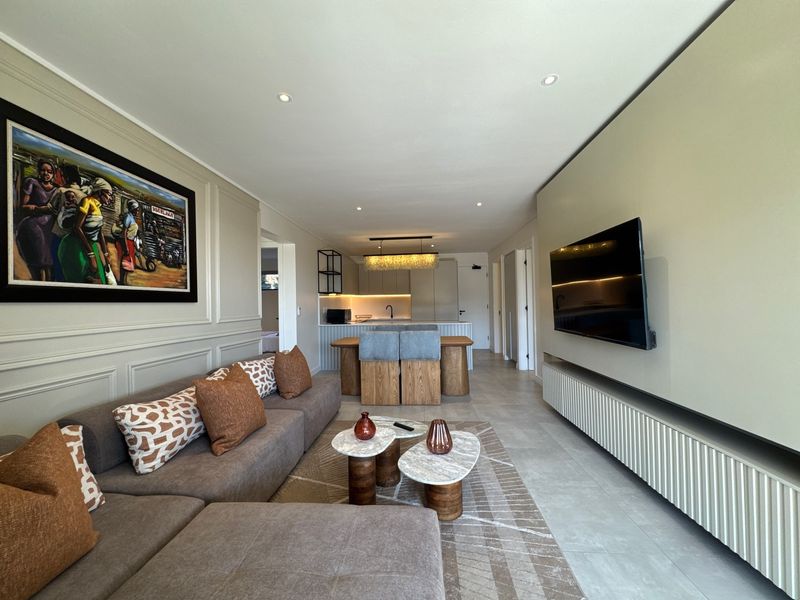 Modern open-plan living and kitchen area featuring contemporary cabinetry, recessed lighting, tiled floors, and a sleek built-in media console.
