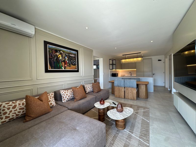 Modern open-plan living area featuring elegant wainscoting, tiled flooring, and a sleek kitchen with integrated cabinetry and island, creating a cohesive and stylish space.