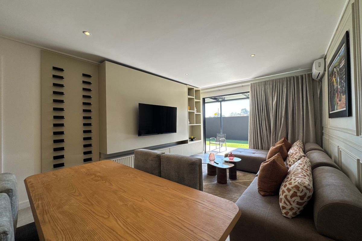 Modern living room featuring a custom built-in media wall, recessed lighting, wainscoting, and large sliding glass doors leading to an outdoor area.