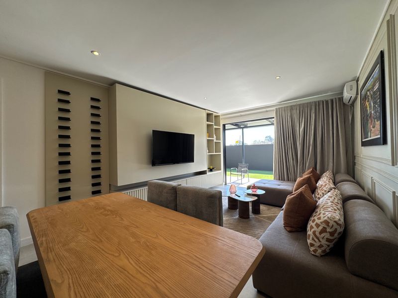 Modern living room featuring a custom built-in media wall, recessed lighting, wainscoting, and large sliding glass doors leading to an outdoor area.